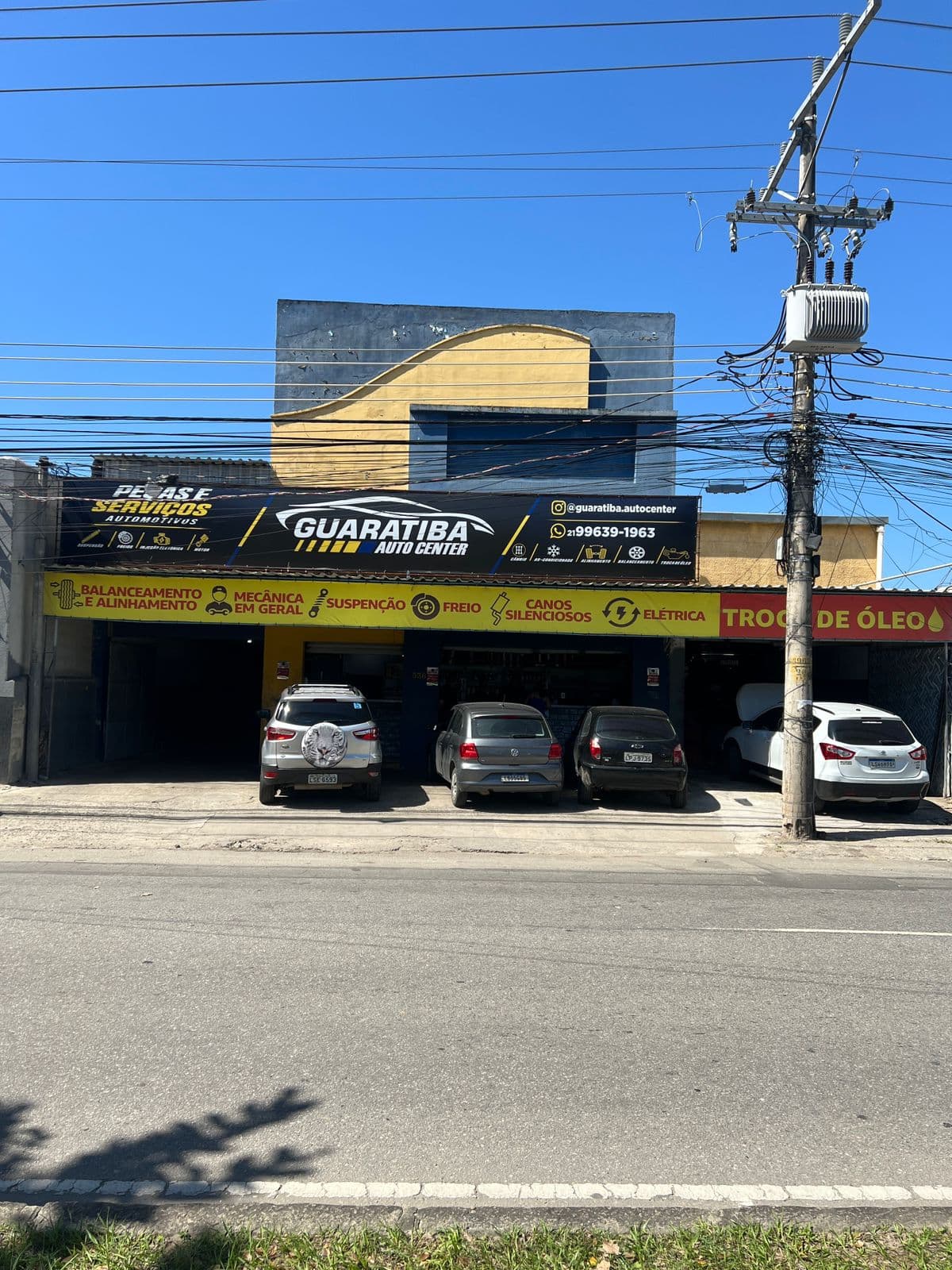 Fachada real da Guaratiba Auto Center na Estrada da Matriz, 536, em Pedra de Guaratiba, com carros sendo atendidos